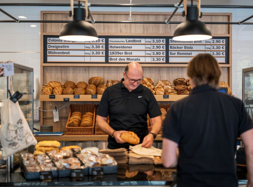 Ein Bäcker verkauft ein Brot in der hauseigenen AXA-Backstube