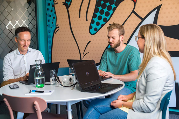 Azubis und Ausbildungsleiter sitzen gemeinsam in Meetingraum