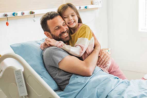 Vater sitzt bei Tochter am Krankenbett