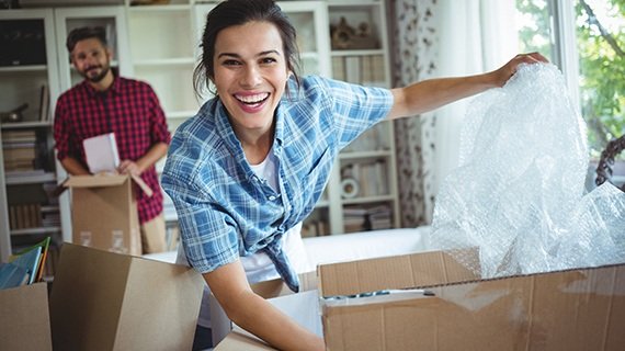Paar packt Umzugskisten in der Wohnung aus