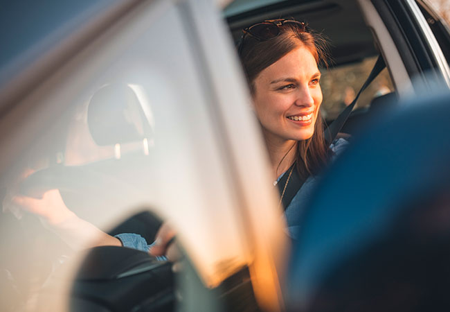 Lächelnde Frau sitzt in ihrem Wagen