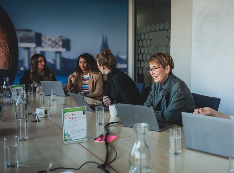 AXA Mitarbeitende diskutieren in Meetingraum bei guter Atmosphäre